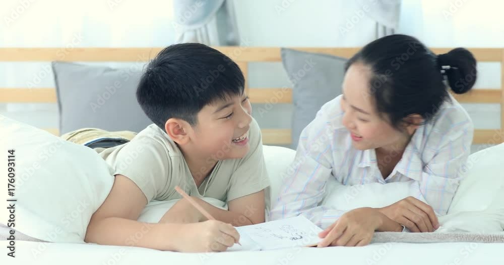 Happy Asian brother and sister rest on the bed and writing with smile face . Happy Asian brother and sister rest on the bed and writing with smile face .