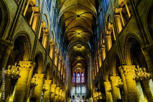 mystical image of the interior of Notre Dame cathedral In Paris with candles of lit faithful illuminated by colored stained glass windows