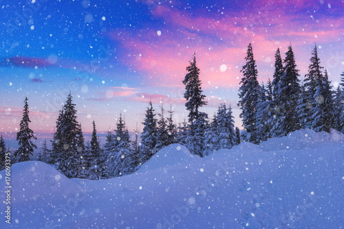Winter fairytale landscape, beautiful sunset during snowfall in the mountain ...