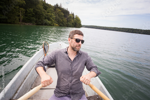 A man is rowing a rowboat on a lake.