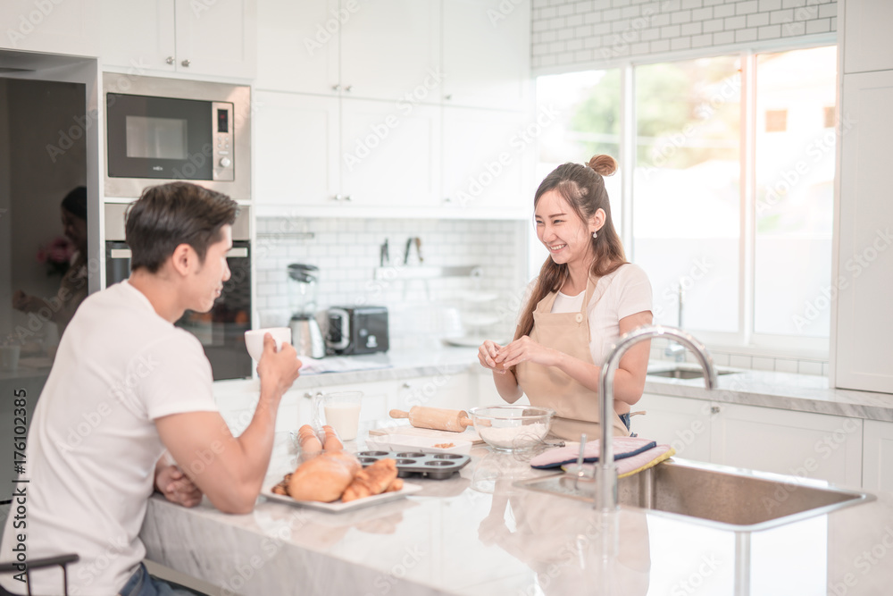 Man drinks coffee while a woman prepares a meal Man drinks coffee while a woman prepares a meal