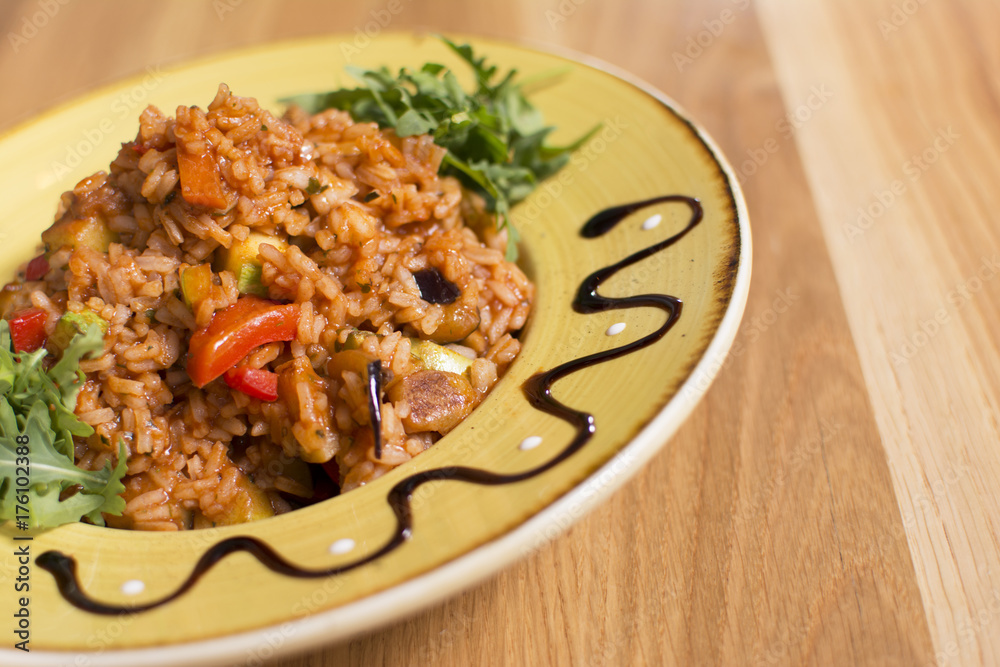 A plate of rice with vegetables. Appetizing healthy rice with vegetables in white plate on a wooden background. A plate of rice with vegetables. Appetizing healthy rice with vegetables in white plate on a wooden background.