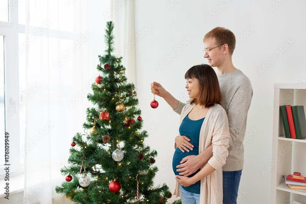 happy pregnant wife and husband at christmas tree happy pregnant wife and husband at christmas tree