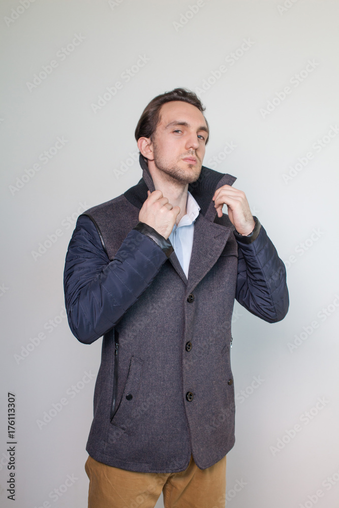 Stylish young man showing a winter coat on a white studio background. Style. Beauty. Fashion. Season Stylish young man showing a winter coat on a white studio background. Style. Beauty. Fashion. Season