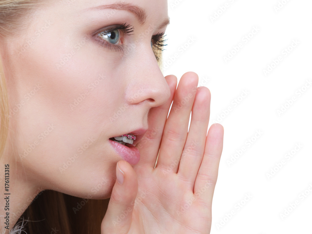 Young blonde woman whispering with hand near mouth Young blonde woman whispering with hand near mouth
