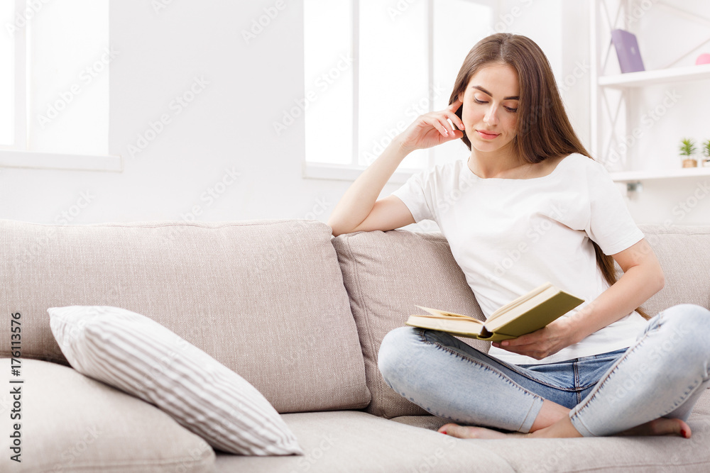 Young brunette woman reading the book at home on the couch. Young brunette woman reading the book at home on the couch.