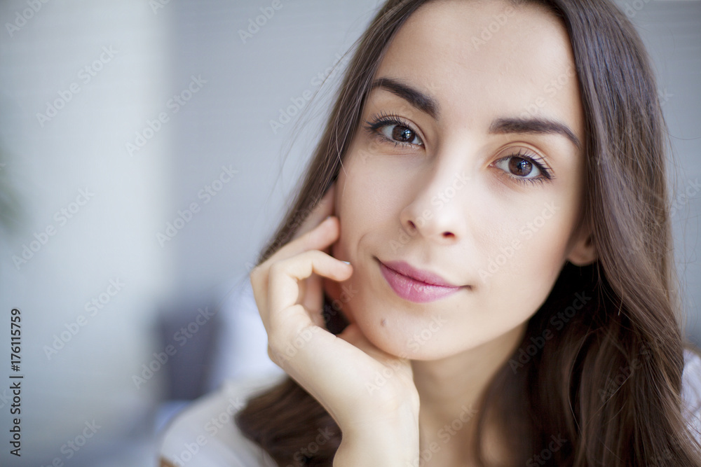 Portrait of Beautiful young brunette woman sitting at the end of the white bed. Portrait of Beautiful young brunette woman sitting at the end of the white bed.
