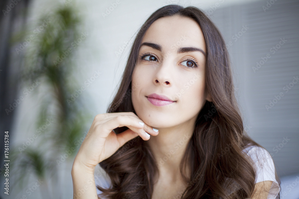 Portrait of Beautiful young brunette woman sitting at the end of the white bed. Portrait of Beautiful young brunette woman sitting at the end of the white bed.