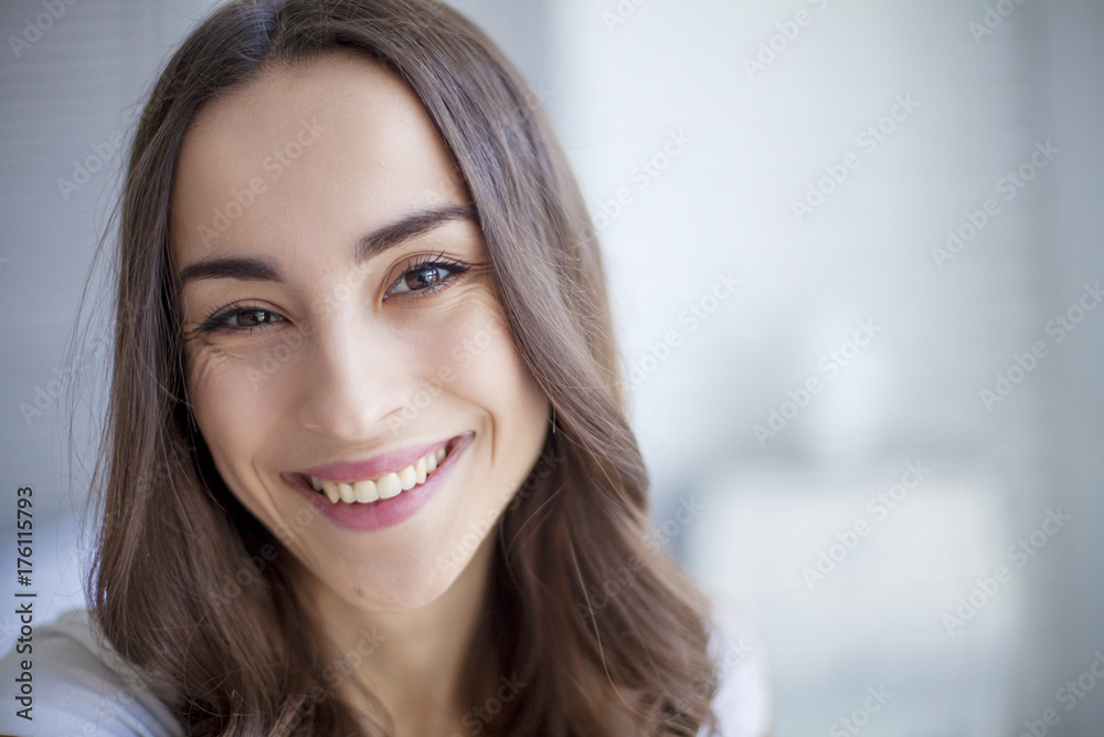 Portrait of Beautiful young brunette woman sitting at the end of the white bed and smiling. Portrait of Beautiful young brunette woman sitting at the end of the white bed and smiling.