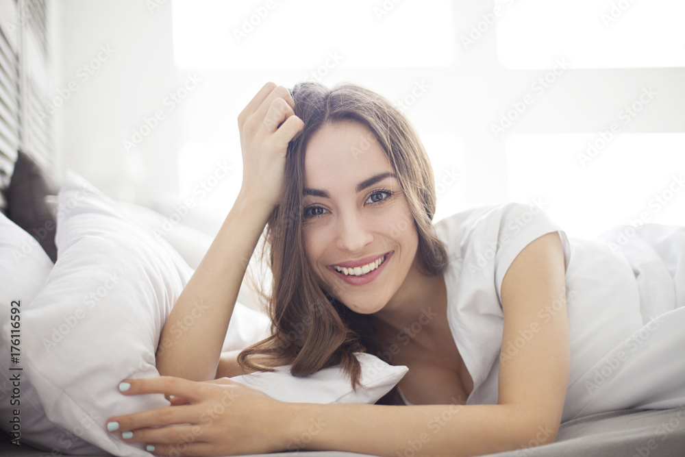 Bedroom. Happy beautiful brunette woman in white bed waking up. Bedroom. Happy beautiful brunette woman in white bed waking up.