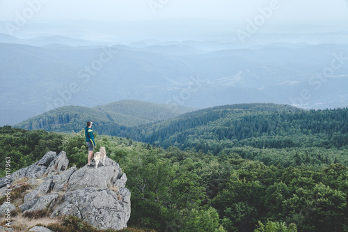 Man with his dog at the top of a mountain having a beautiful view photo