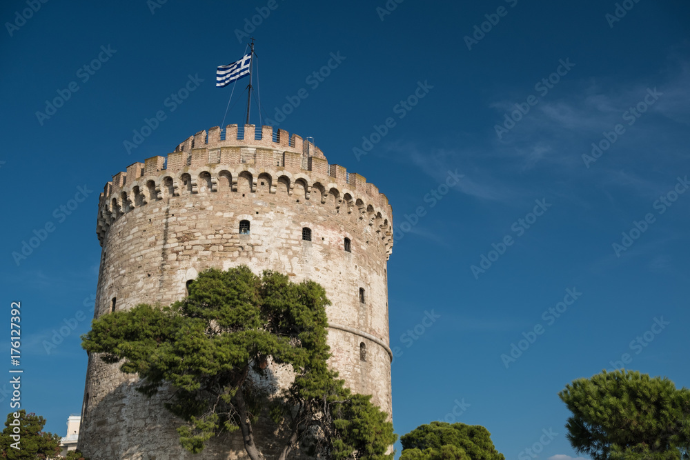 Ancient stone tower with Greek flag on the top