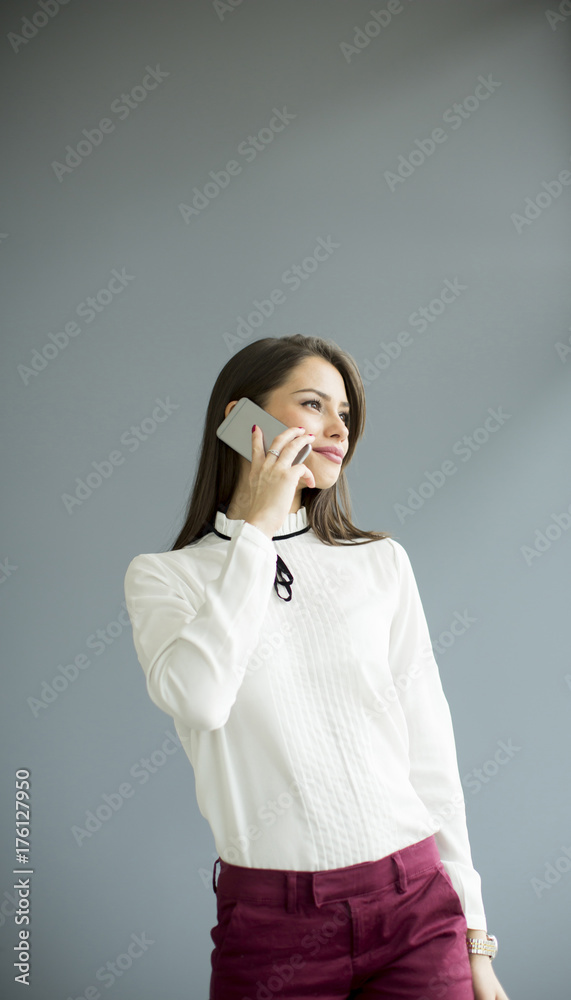 Elegant businesswoman with mobile phone by the wall Elegant businesswoman with mobile phone by the wall
