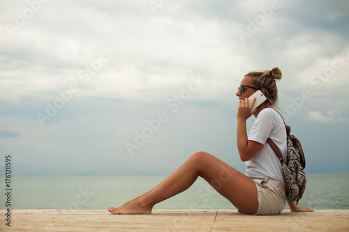 Happy young woman on beach talking phone