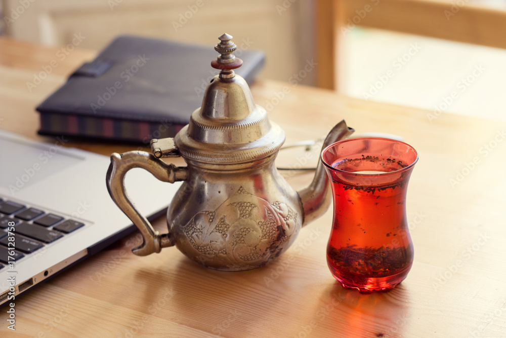 office desk gray laptop silver arabic tea pot and notebook red cup office desk gray laptop silver arabic tea pot and notebook red cup