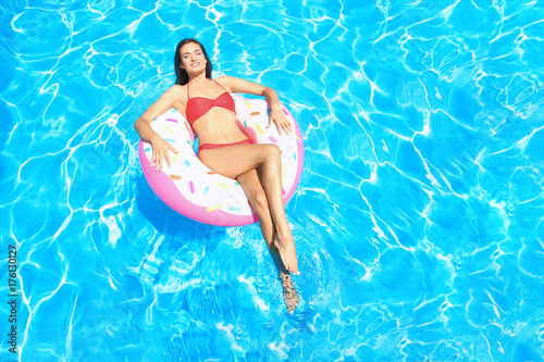 Young beautiful woman sunbathing on inflatable ring in swimming pool
