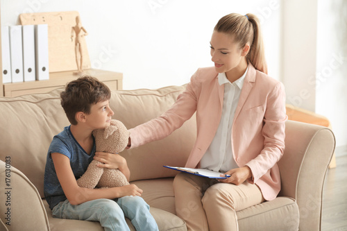 Young psychologist working with little boy in office