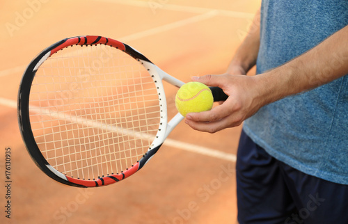 Man with tennis racket and ball standing on court © Africa Studio