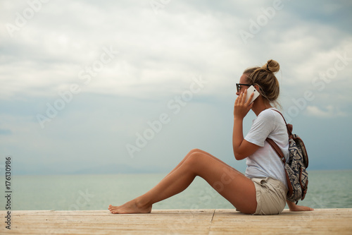 Young woman using phone on seacoast