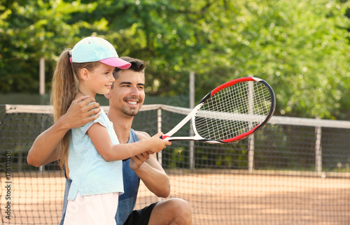 Young trainer with little girl on tennis court © Africa Studio