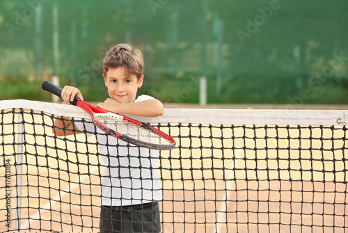 Cute little boy with tennis racket on court © Africa Studio