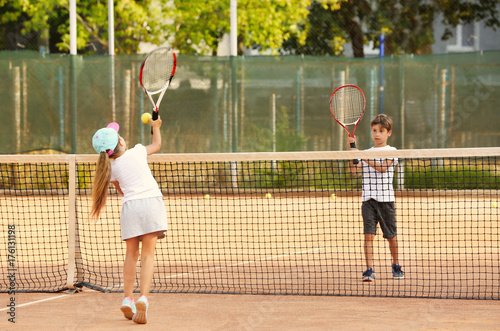 Cute little children playing tennis on court