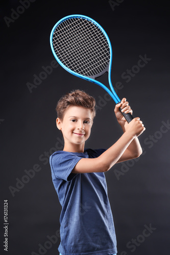 Cute little boy with tennis racket on dark background © Africa Studio