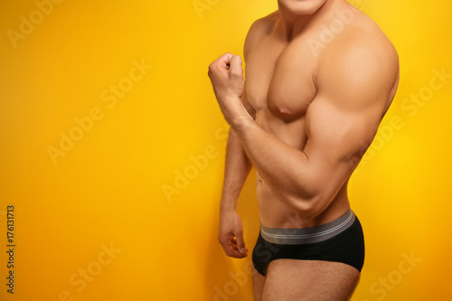 Muscular man in underwear on color background
