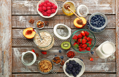 Composition with nutritious oatmeal and different ingredients for breakfast on wooden background