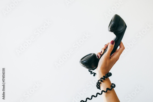 woman holding a telephone with cord wrapped around wrist photo