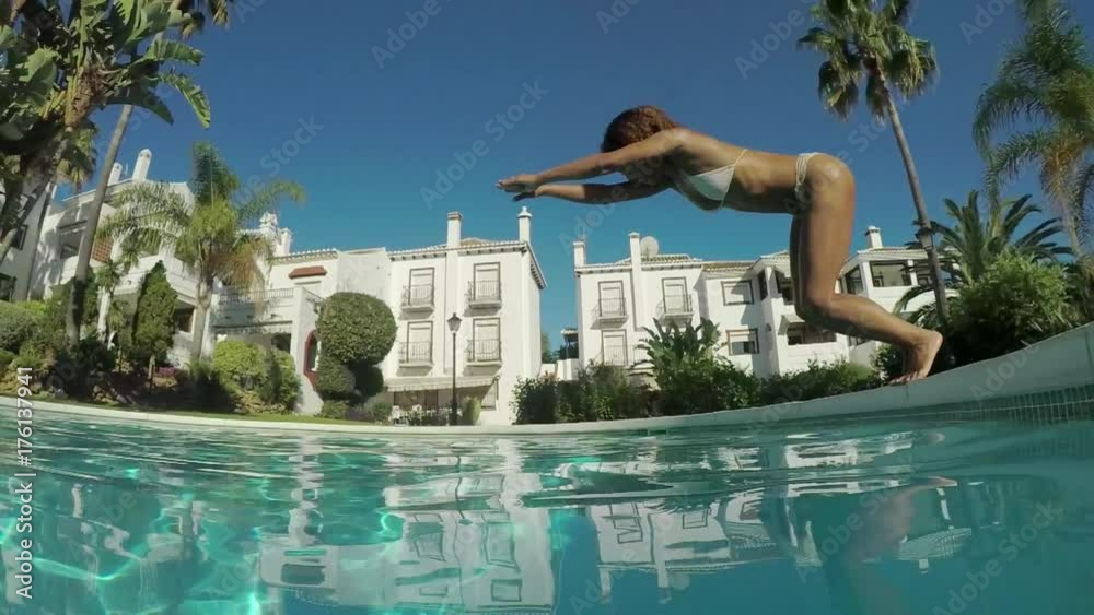 Side view of attractive woman diving in water while resting at pool in sunny day.