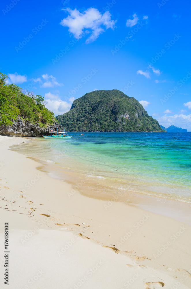 Sandy beach with an traditional banca boat in clear water, El Nido, Palawan, Philippines