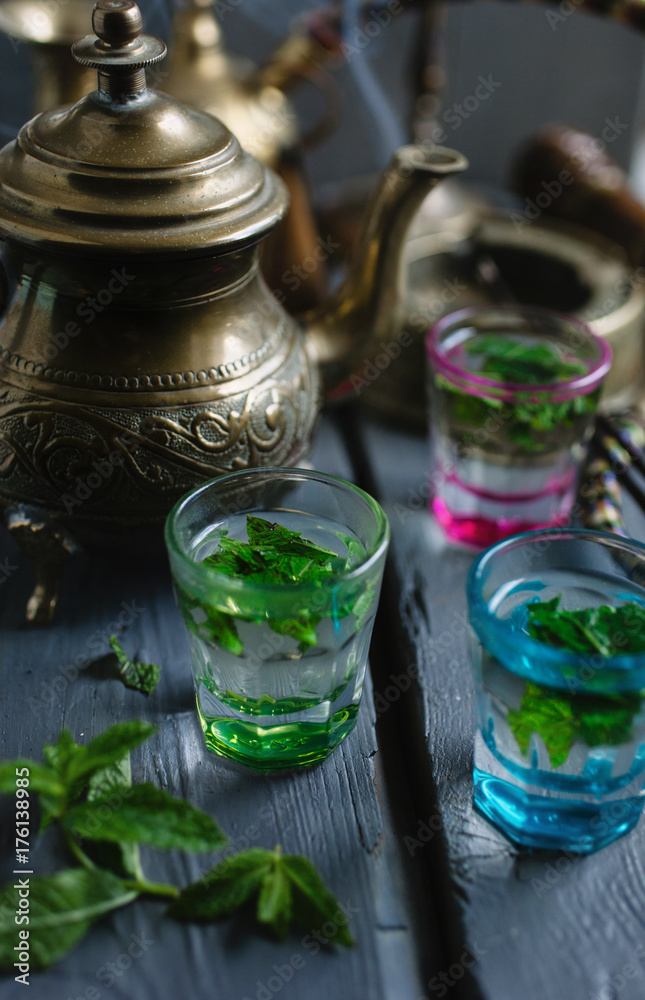 Mint tea in glasses on a table with teapot and incense burning in background. Mint tea in glasses on a table with teapot and incense burning in background.