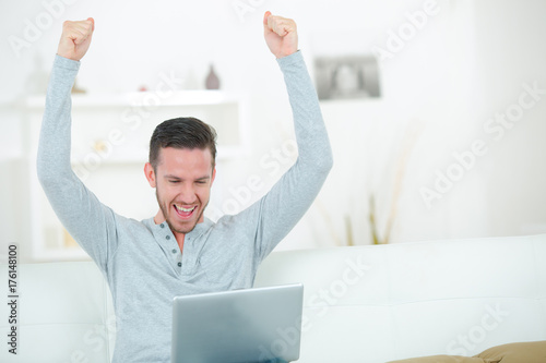 Valokuva Man using laptop making triumphant gesture