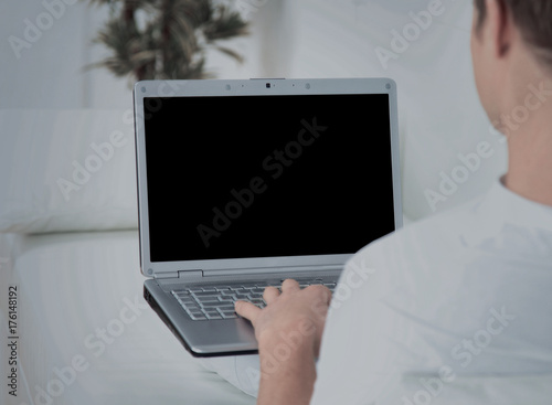 Rear view closeup of a young man working of a laptop