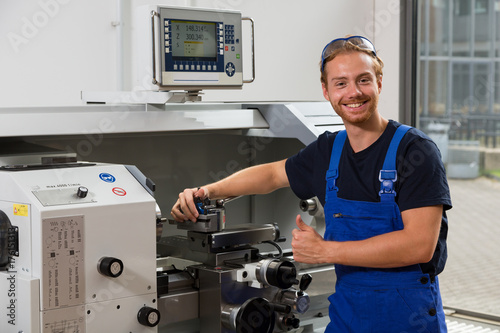Worker or fitter posing in front of turning machine at workshop