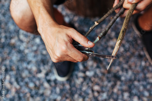 A caucasian man whittling a stick outdoors for roasting s'mores. photo