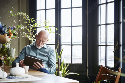 Senior Man Using Digital Tablet At Table photo