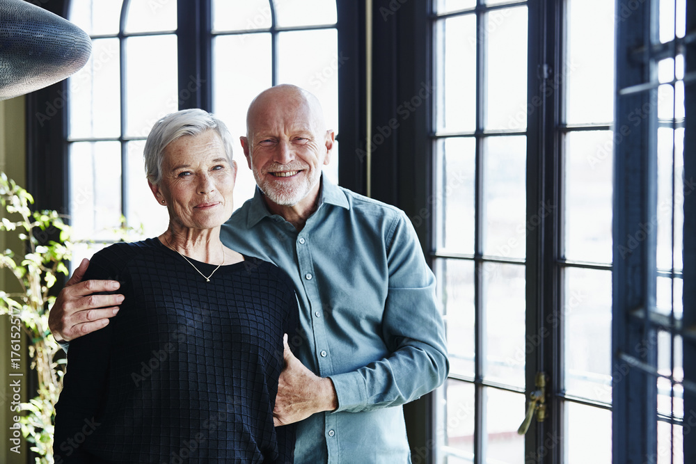 Happy Senior Couple Standing By Window At Home Happy Senior Couple Standing By Window At Home