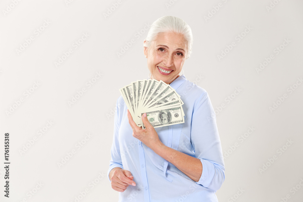 Beautiful smiling elderly lady holding fan of money, looking at camera Beautiful smiling elderly lady holding fan of money, looking at camera