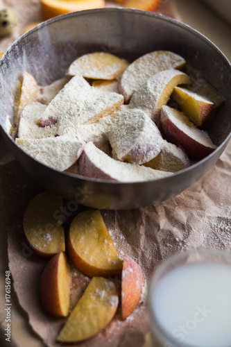 Fresh red apple slices sprinkled with flour in a stylish iron dish lying on a white window sill. A glass of milk are used as decoration. photo