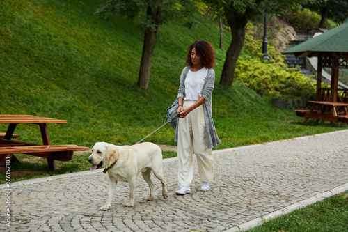 Pretty young lady walking with dog in park in the morning photo