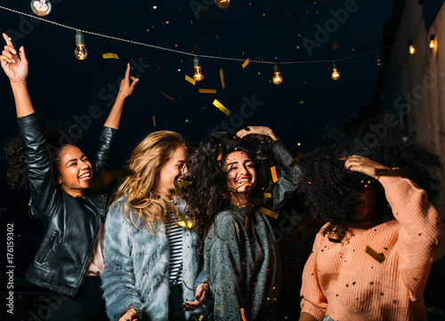 Group of young women having a party at night, dancing on a terrace