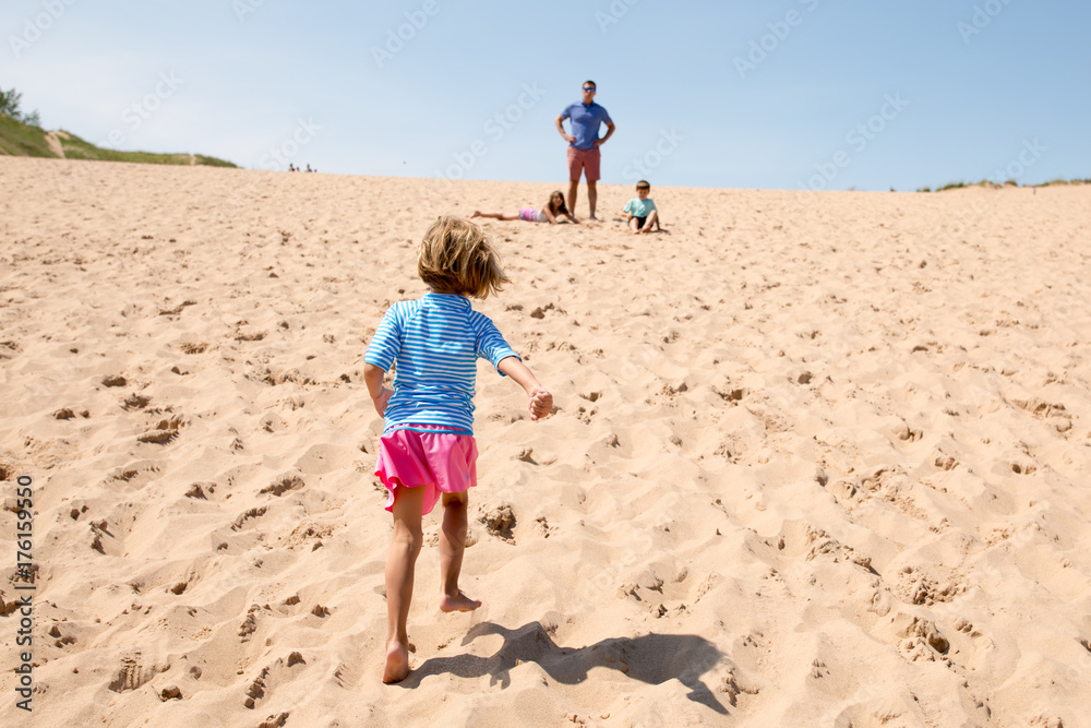 Father with children on beach, girl running towards father, rear view Father with children on beach, girl running towards father, rear view