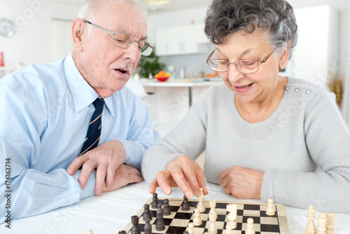 elderly man and woman playing chess at home