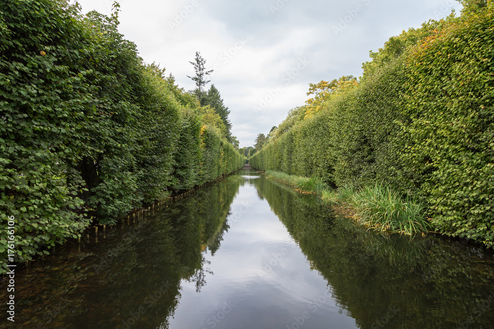 View of a water canal and lush hedge at the Oliwa Park (Park Oliwski). It's a public park in Gdansk, Poland.