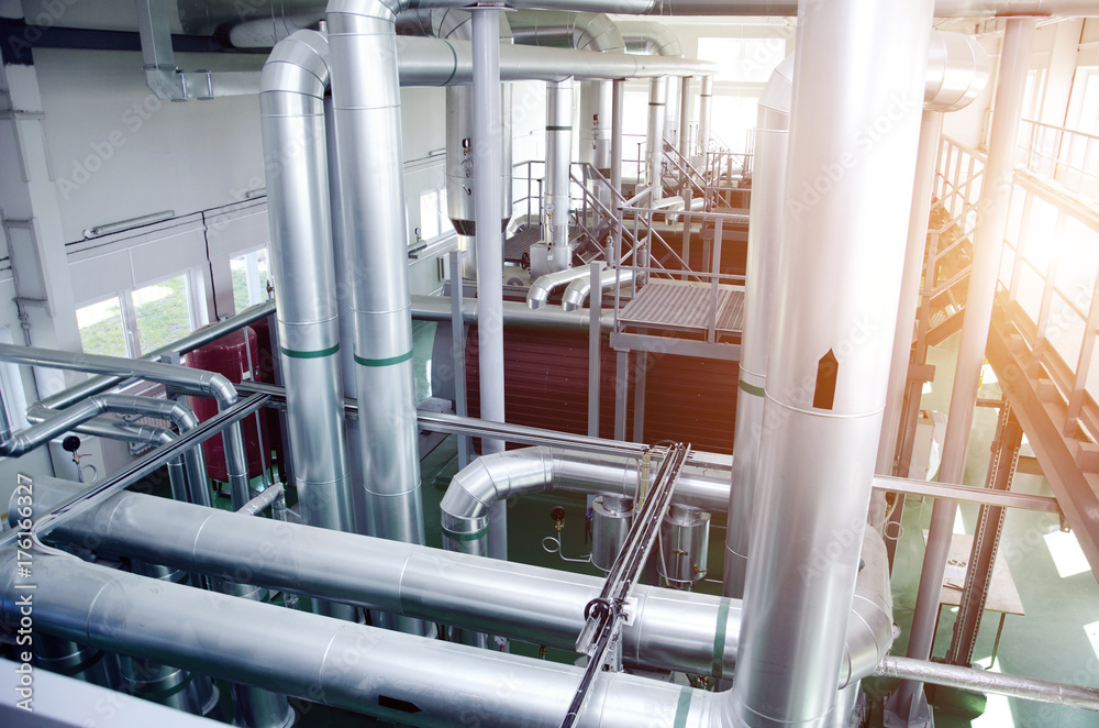 The interior of a modern industrial gas boiler room. Pipelines, water pumps, valves, manometers.