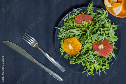 Green salad of arugula on a plate with slices of orange and grapefruit