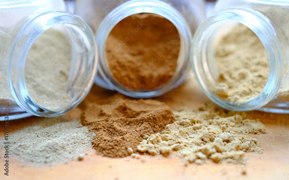 Ground spices - cinnamon, ginger and cardamom - spill out from small jars. Soft selective focus. Ground spices - cinnamon, ginger and cardamom - spill out from small jars. Soft selective focus.