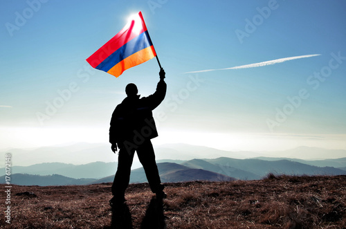 Fotografie Successful silhouette man winner waving Armenian flag on top of the mountain pea